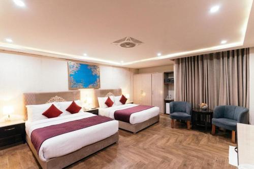 a hotel room with two beds and a desk at Shelton's Ambassador Hotel Blue Area in Islamabad