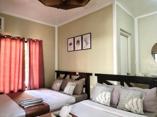two beds in a room with red curtains at Panari Lodge El Nido in El Nido