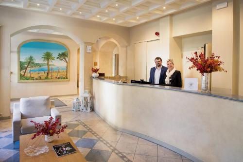 a man and a woman standing at a counter in a salon at Albergo Belsoggiorno in Sanremo
