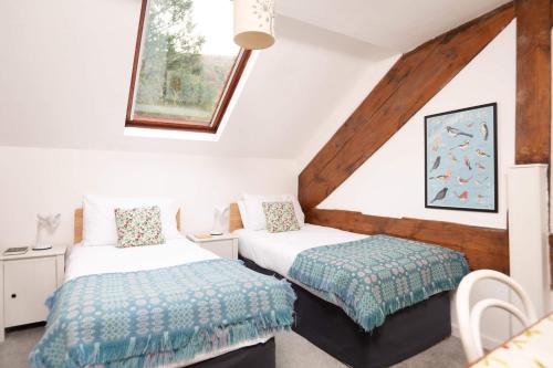 a bedroom with two beds and a window at Ty'r Adar at Graig Wen in Arthog