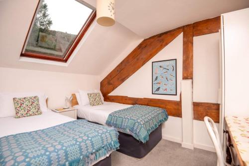 a attic room with two beds and a window at Ty'r Adar at Graig Wen in Arthog