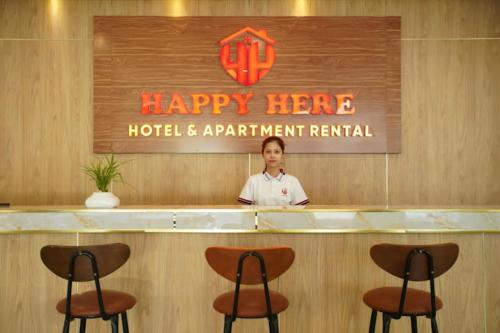 un hombre parado detrás de un mostrador en un feliz hotel y alquiler de apartamentos en Happy Hotel Here, en Nha Trang