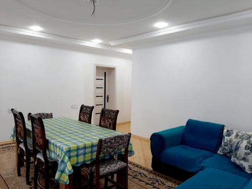 a dining room with a table and a blue couch at Samira's house Gusar in Hǝsǝnqala