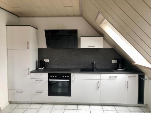 a kitchen with white cabinets and a sink and a stove at Die Kirsche in Achern