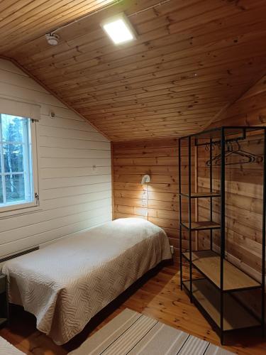 a bedroom with a bed in a wooden cabin at Mäkelän Lomatuvat Cottages in Korkeakoski