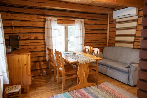 ein Esszimmer mit Tisch und Couch in der Unterkunft Mäkelän Lomatuvat Cottages in Korkeakoski