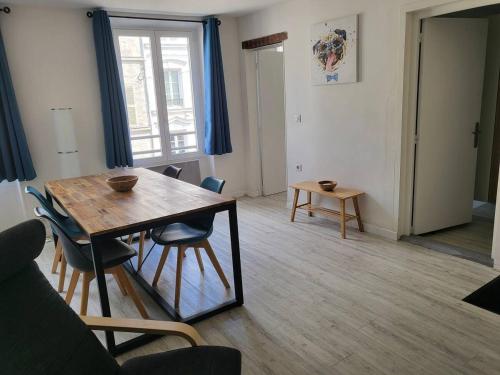 un salon avec une table et des chaises en bois dans l'établissement Appartement hypercentre Fontainebleau, à Fontainebleau