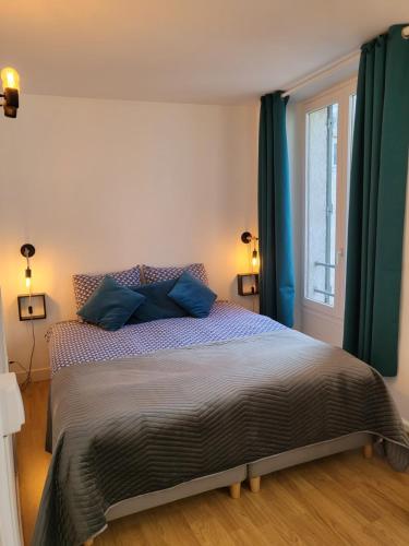 une chambre avec un lit avec des oreillers bleus et une fenêtre dans l'établissement Appartement hypercentre Fontainebleau, à Fontainebleau
