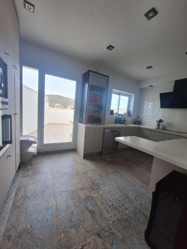 a large kitchen with white counters and a large window at Ático Dúplex Baladrar Gran Terraza 8Km Playa Dénia-Oliva Nova Golf -IDEAL Familias y Grupos in Pego