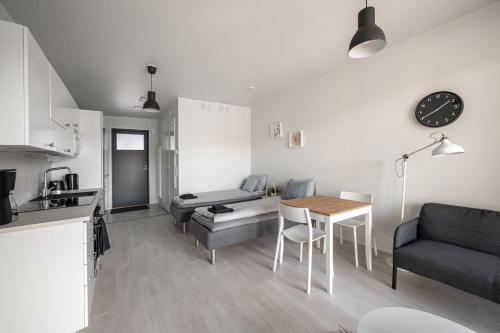 a kitchen and a living room with a table and a couch at Vesirattaantie Apartment in Espoo
