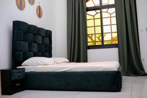 a bedroom with a bed with a headboard and a window at Les Jardins de René Hébergements in Yaoundé