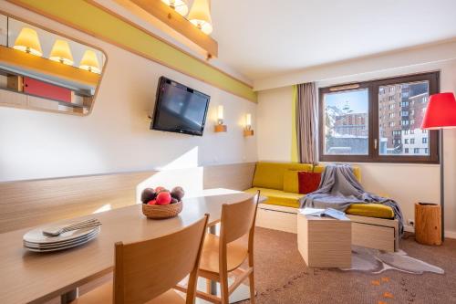 a living room with a table and a yellow couch at Résidence Pierre & Vacances Electra in Avoriaz