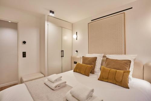 - une chambre blanche avec un grand lit blanc et des oreillers bruns dans l'établissement Superb Apartment Center of Paris by Studio prestige, à Paris