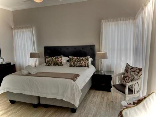 a bedroom with a large bed and a chair at Villa De Mer in Port Alfred