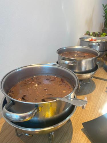 a row of metal pots filled with food on a table at Royal Design Savassi Hotel in Belo Horizonte