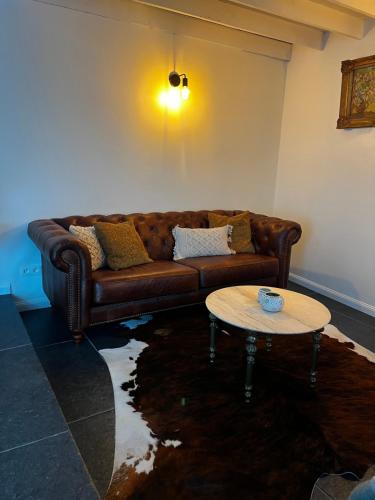 a living room with a brown couch and a table at Melkhuisje in Dendermonde