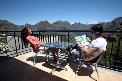 a man and a woman sitting at a table reading a book at Eira do Serrado - Hotel & Spa in Curral das Freiras