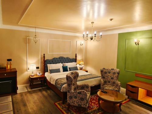 a bedroom with a bed and two chairs at juSTa Birding Resort & Spa - Best Dhauladhar View Resort in Dharamshala