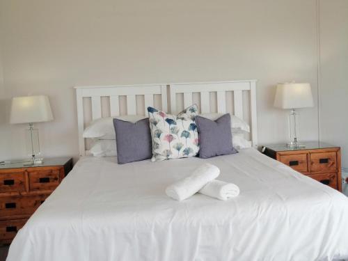 a white bed with two pillows and towels on it at Villa De Mer in Port Alfred