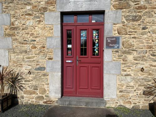 a red door on the side of a stone building at Le Clos des Tilleuls D Day Home, Chambres d'hôtes, Suite avec Sauna Privatif, Suite avec balnéothérapie privative, en supplément option SPA bain à remous in La Vendelée