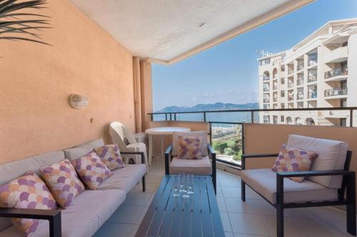 un balcon avec un canapé, des chaises et une table dans l'établissement L'AZUR avec terrasse vue mer, piscine accessible et près des plages, à Cannes