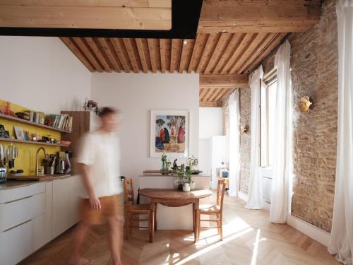 un homme qui marche dans une cuisine avec une table dans l'établissement Le canut, à Lyon