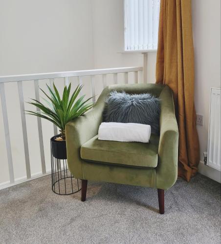 a green chair with a pillow on it next to a plant at Beautiful 2 Bed House, Central spot with free parking in Wakefield
