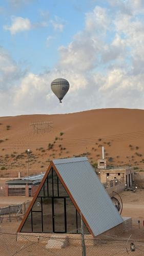 a hot air balloon flying over a building in a desert at Bidiya Desert Camp in Aflāj