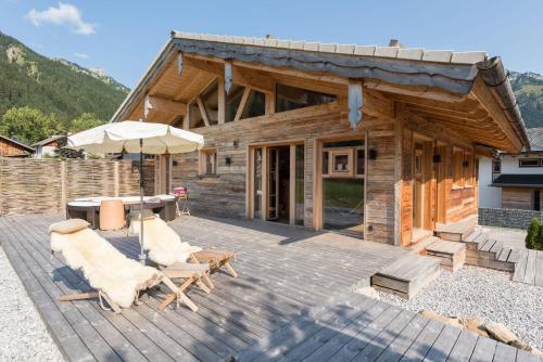 a log cabin with a table and chairs and an umbrella at Chalet Grand Flüh - Alpiner Luxus & Spa in Nesselwängle