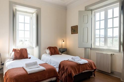 a bedroom with two beds and two windows at Herdade da Ordem in Cabeço de Vide