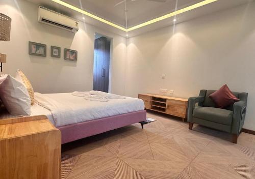 a bedroom with a bed and a chair in a room at VILLA M- SAVANNAH 7- 5BHK Brand New Villa in Calangute with Private Pool, Near Beach, free Breakfast, north goa in Goa