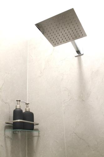 a shower with a black soap dispenser on a wall at Dimora Vannucchi in San Giorgio a Cremano