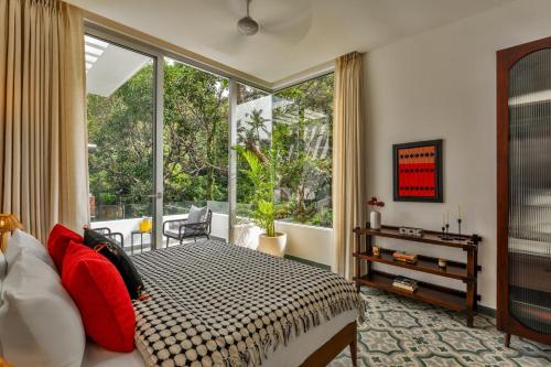a bedroom with a bed and a large window at La Masillia, 2 BHK with Private Pool, 15 mins from Morjim Beach, Wifi, Peaceful location, Kitchen, Security, Patio in Siolim
