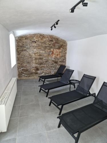 a row of black chairs in a room with a brick wall at Černý Potok 59 in Kryštofovy Hamry