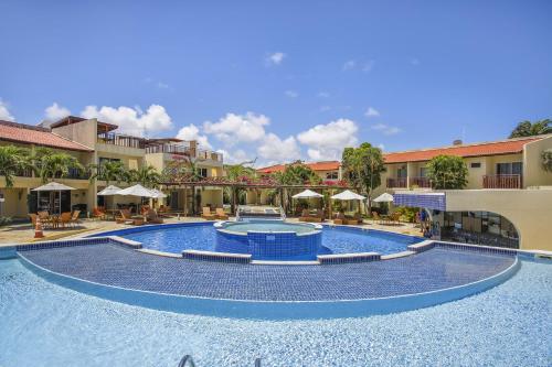 a large swimming pool in a resort with chairs and umbrellas at TRIPLEX Solar Água- by Pipa Praia House in Pipa