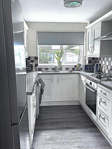 a kitchen with white cabinets and a window at Luxury Home in Luton - Near L&D Hospital - FREE Netflix & Wifi- FREE Parking in Lewsey