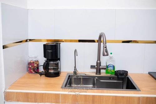 a kitchen counter with a sink and a coffee maker at Les Jardins de René Hébergements in Yaoundé