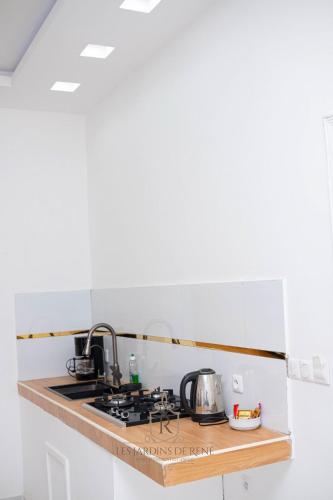 a kitchen counter with a sink and a stove at Les Jardins de René Hébergements in Yaoundé