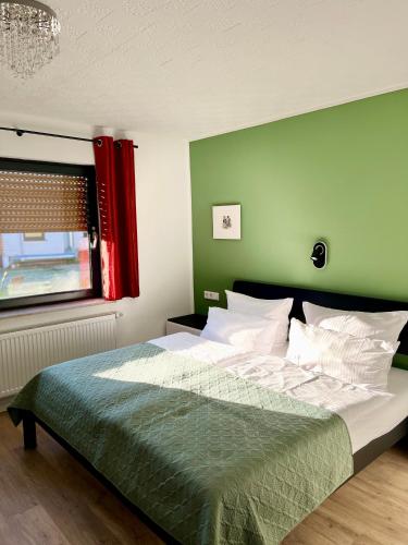 a bedroom with a large bed with a green wall at Berghotel Waidmannsheil in Battenberg
