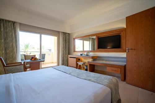 a hotel room with a bed and a desk and a television at Serenity Alma Heights - Ex Serenity Fun City in Hurghada