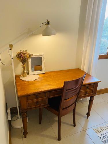 - un bureau en bois avec un miroir et un vase de fleurs dans l'établissement Le Hibou Heureux, à Bézenac