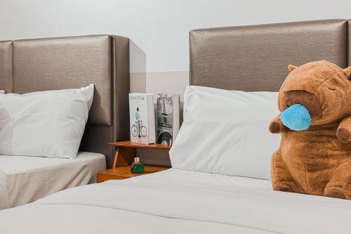 a stuffed teddy bear sitting on a bed at Taiping Rain Suite Homestay near Lake Garden with Netflix WiFi in Taiping
