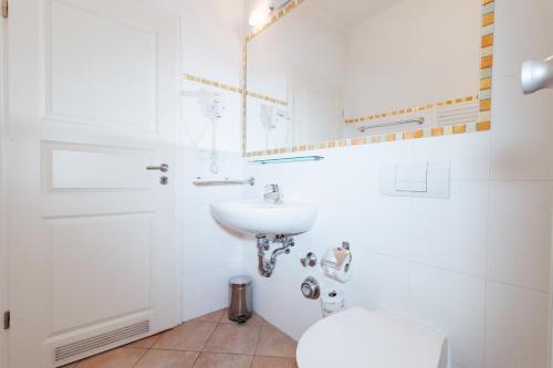 a white bathroom with a sink and a toilet at Villa Laetitia Whg 24 in Binz