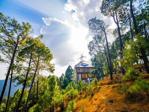 a house on top of a hill with trees at The Hosteller Lansdowne in Lansdowne