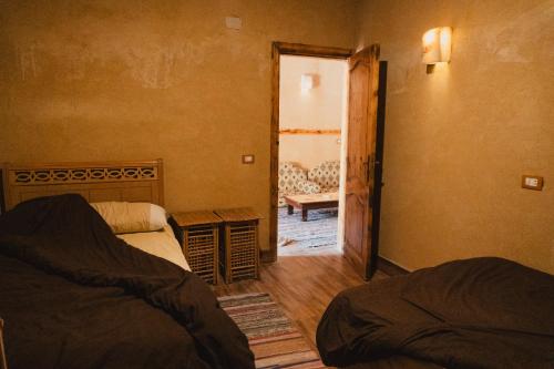 a bedroom with two beds and a door to a room at Stamps Ayur Siwa in Siwa