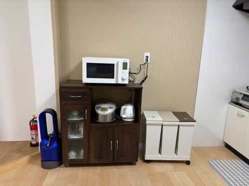a microwave on a stand in a room at サンライズハウス in Osaka