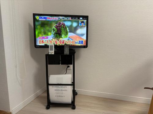 a flat screen tv on a stand with a television on it at サンライズハウス in Osaka