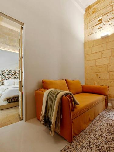 an orange couch in a room with a bedroom at Harbour Heights in Birgu