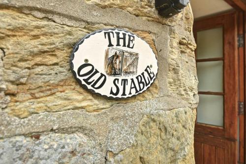 una señal en el lateral de un edificio de piedra en The Old Stable, en Ruswarp