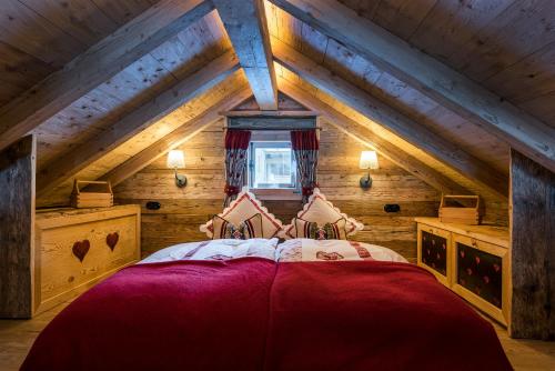 a bedroom with a red bed in a attic at Chalet Grand Flüh - Alpiner Luxus & Spa in Nesselwängle